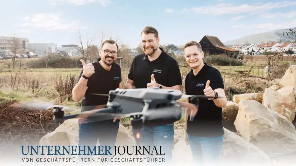 Die drei Geschäftsführer von EnerPlan stehen vor einer Landschaft. Alle zeigen den Daumen nach oben. Vor ihnen fliegt eine Drohne. Das Bild ist für das Unternehmer Journal von Geschäftsführern für Geschäftsführer.