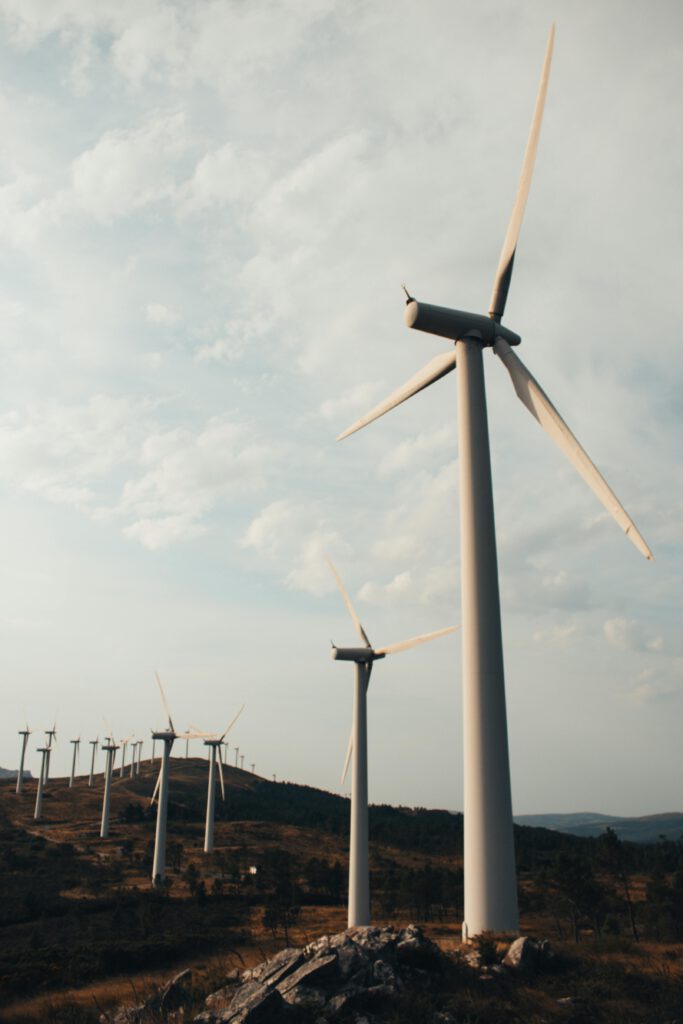 Windpark mit mehreren Windkraftanlagen auf einer hügeligen Landschaft unter bewölktem Himmel